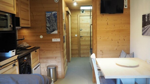 Pieni, käytännöllinen keittiö, jonka seinät ovat puuta. Keittiössä on mikroaaltouuni, liesi ja pesuallas. Lisäksi siellä on ruokapöytä tuoleineen ja seinälle asennettu televisio.