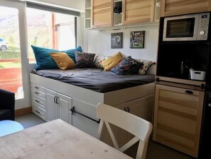 A compact bedroom with a bed, a small table, a chair, and a kitchenette with a microwave. - 50m from ski slopes, Ground floor, balcony, tv, ski locker, 19m², Les Menuires (Les Menuires)