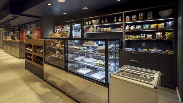 Een bakkerijdisplay met diverse gebakjes en een assortiment verpakte snacks.