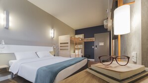 Een moderne hotelkamer met een net opgemaakt bed, een houten bureau met glazen en een garderobe met spiegel.