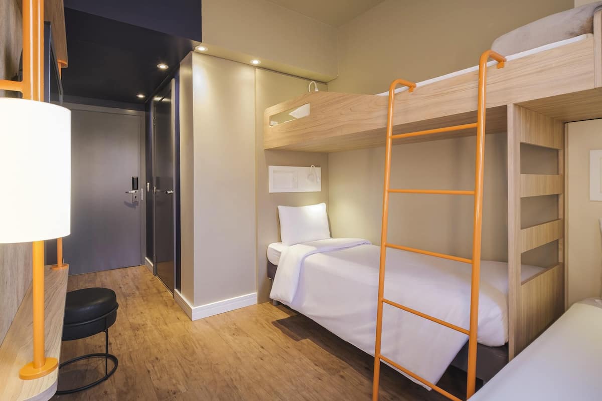 Ein kleines Hotelzimmer mit Etagenbetten, einem Schreibtisch und einem Stuhl.