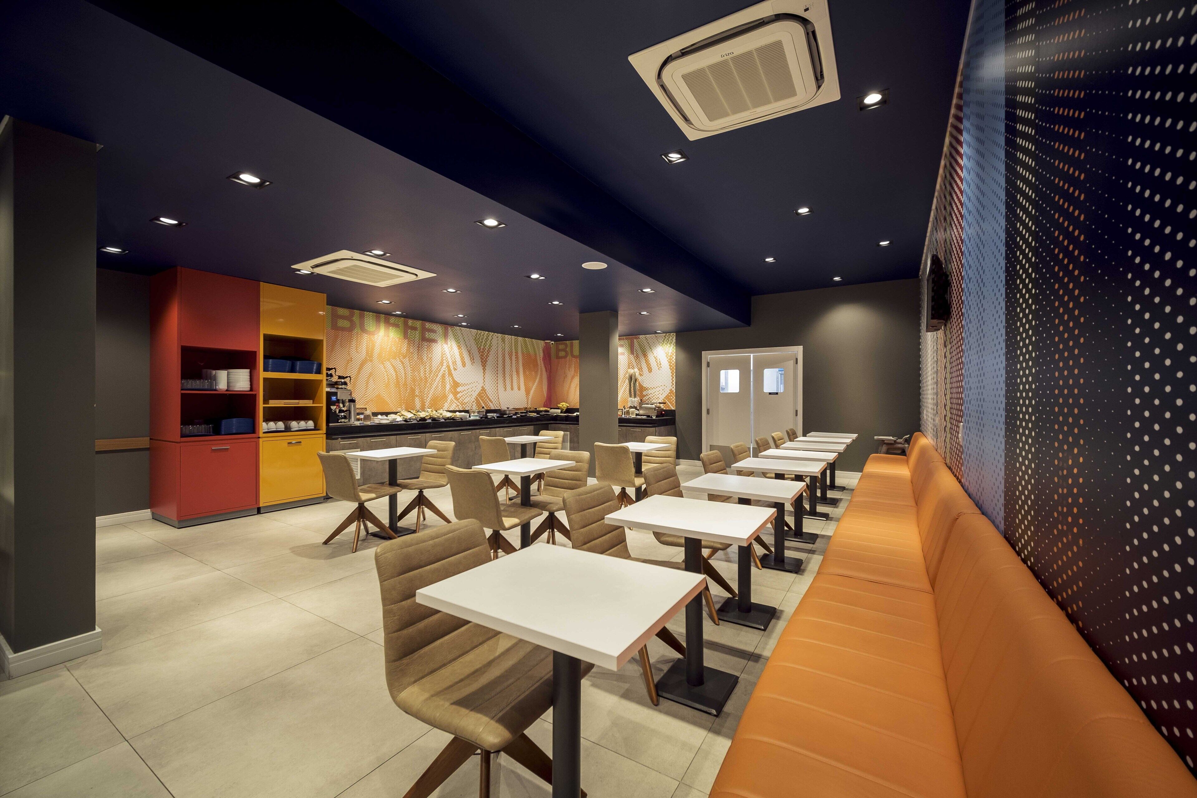 A modern restaurant with booths and tables, a patterned wall, and a ceiling with recessed lighting.