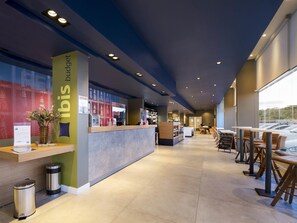 Un moderno vestíbulo de hotel con mostrador de recepción, zona de estar y grandes ventanales.