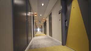 Een hotelgang met deuren aan beide kanten, genummerde deurplaatjes en een tapijtvloer.