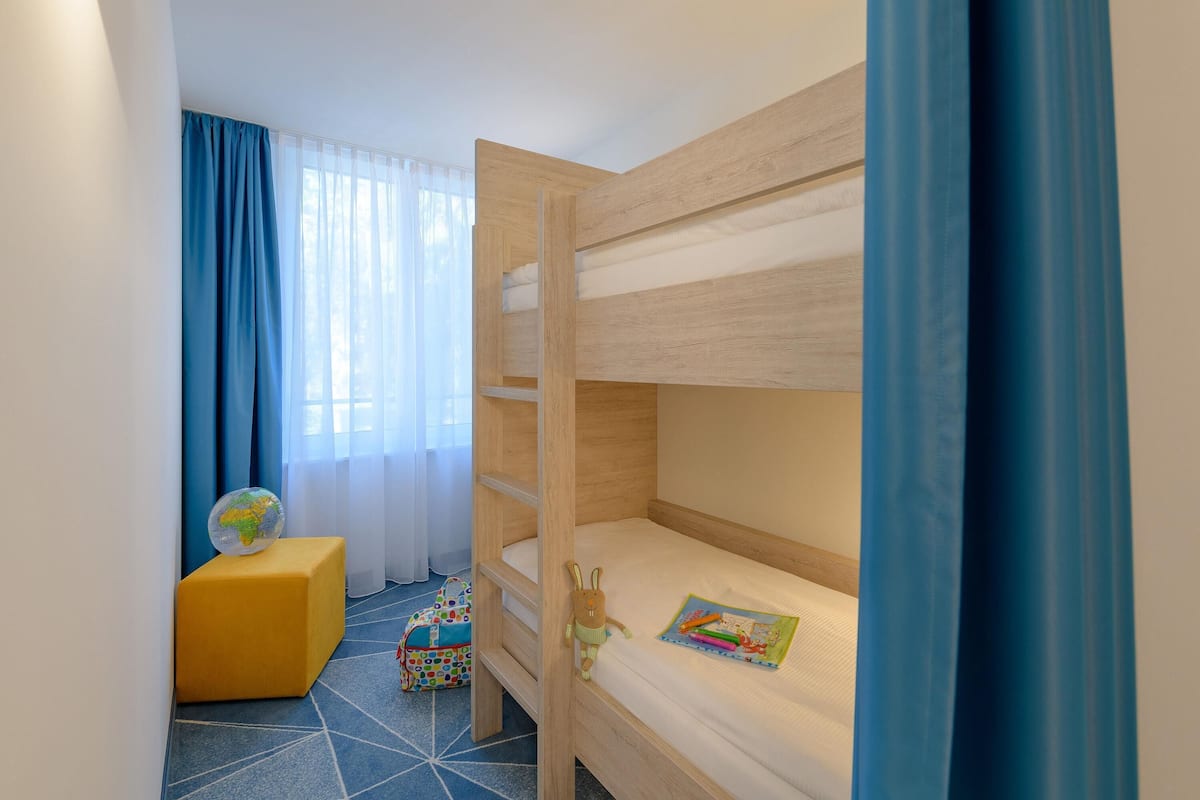 A bunk bed room with a small desk, a globe, and a colorful bag.