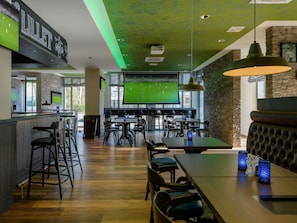 A sports bar with a large screen, wooden bar counter, and multiple seating areas. - ibis Styles Bad Reichenhall (Bad Reichenhall)