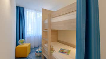 Een slaapkamer met een stapelbed, een klein bureau, een wereldbol en een kleurrijke tas.