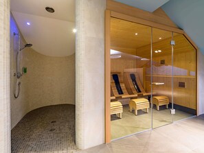 Casa de banho moderna com chuveiro, bancos de madeira e divisória de vidro.