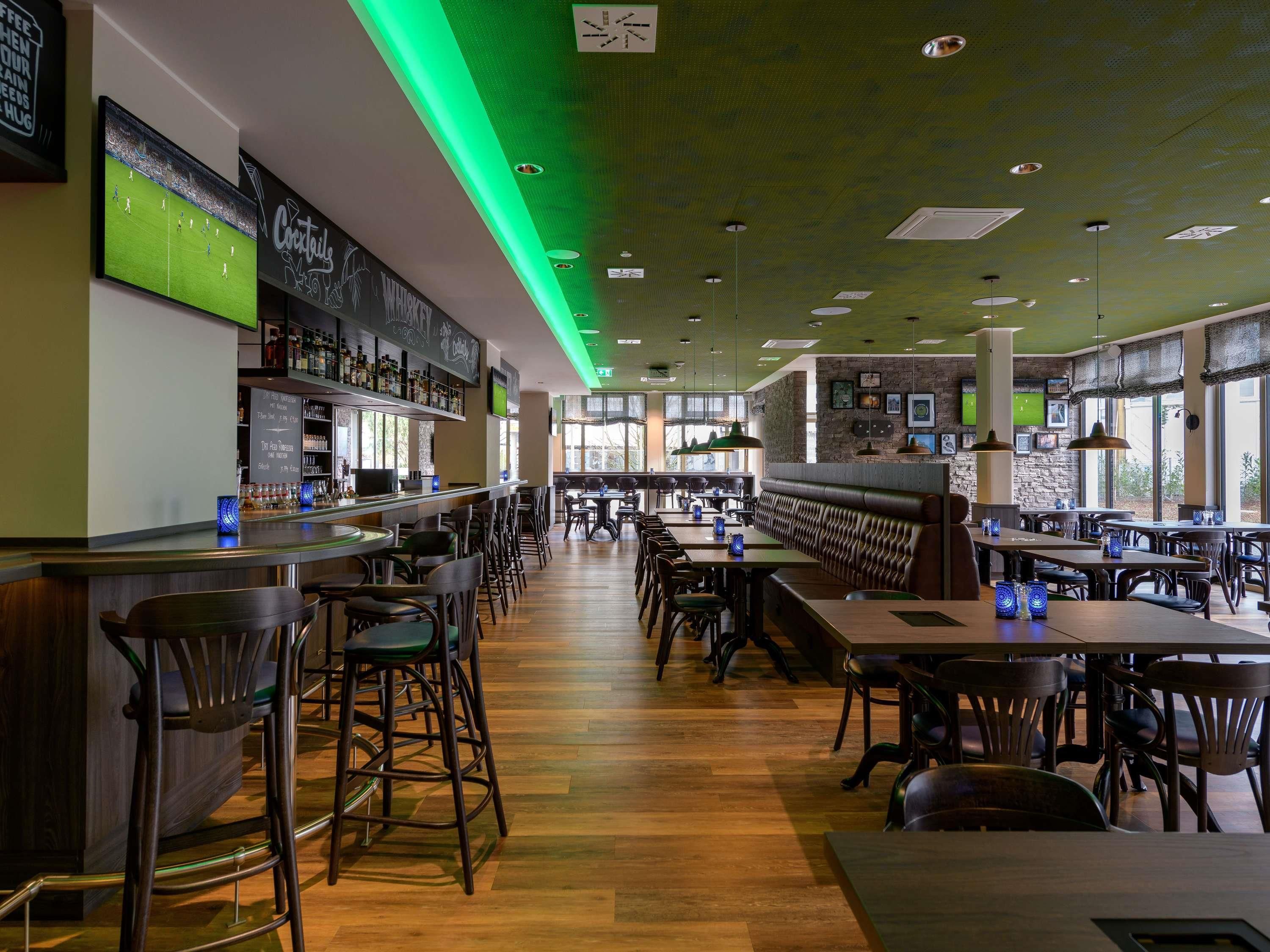 A restaurant with a bar area, booths, and high tables.