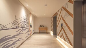 Un couloir avec un banc en bois, une fresque murale et un mur à motifs de marbre.
