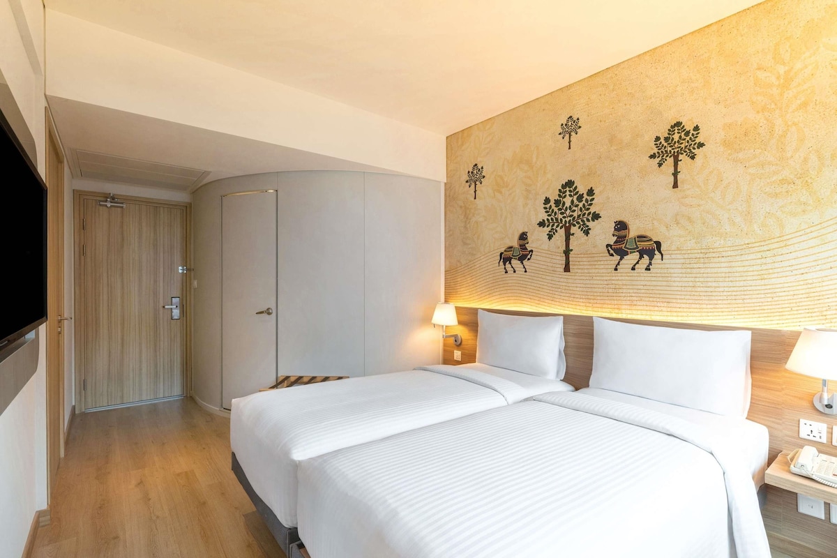 Une chambre d’hôtel équipée d’un lit, d’une télévision, d’une armoire et d’un mur orné d’une fresque.