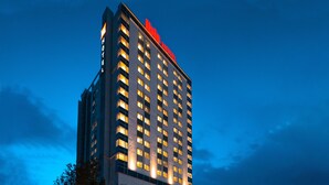 Un grand hôtel, avec de nombreuses fenêtres illuminées et une grande enseigne rouge bien visible au sommet.