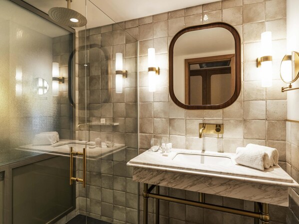 A modern bathroom with a glass-enclosed shower, a marble sink, and a large mirror.
