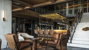 Ett modernt loungeområde med läderfåtöljer, ett runt soffbord och en bar med en glasvitrin.