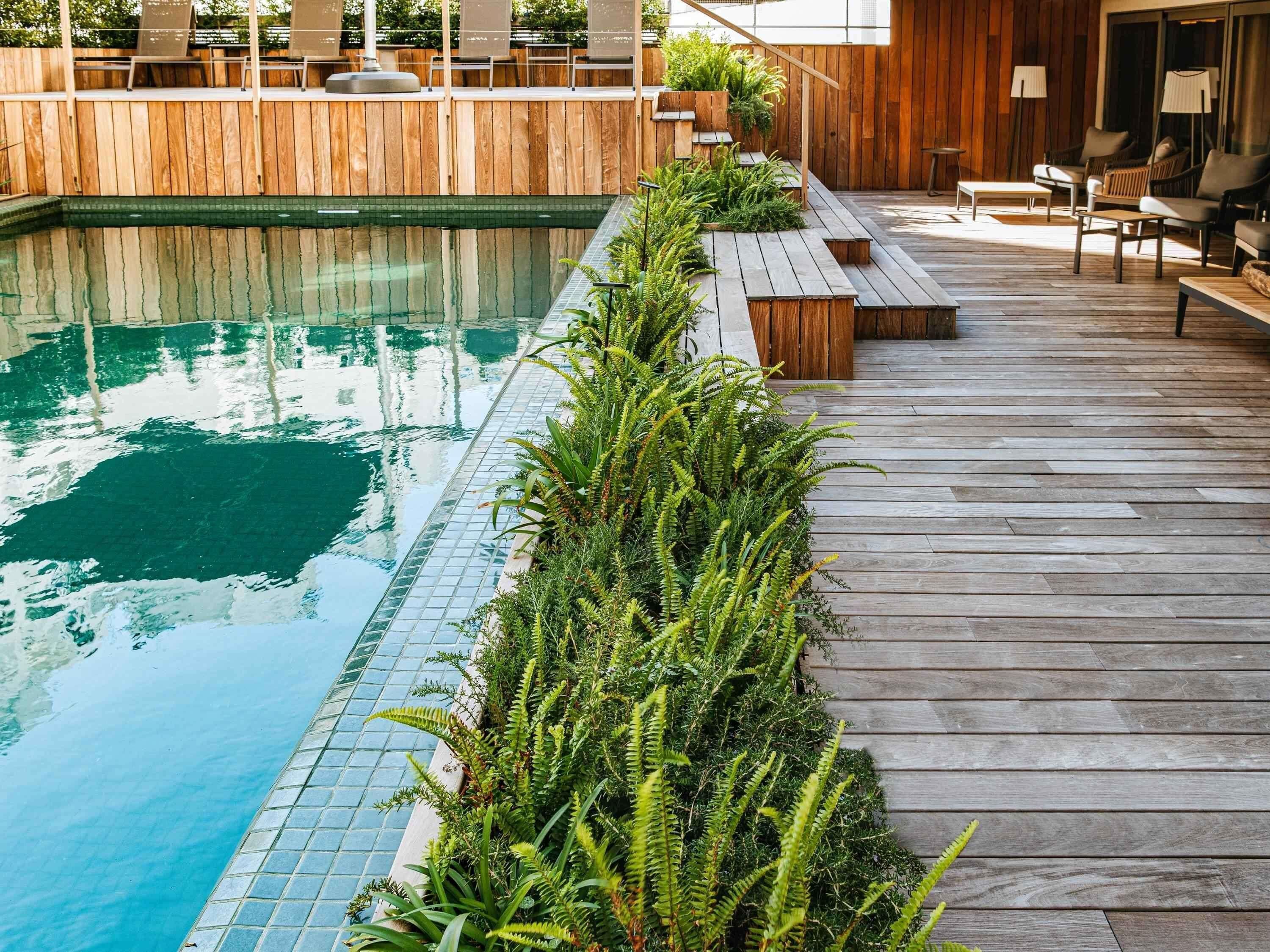 Una piscina al aire libre, sombrillas, sillones reclinables de piscina