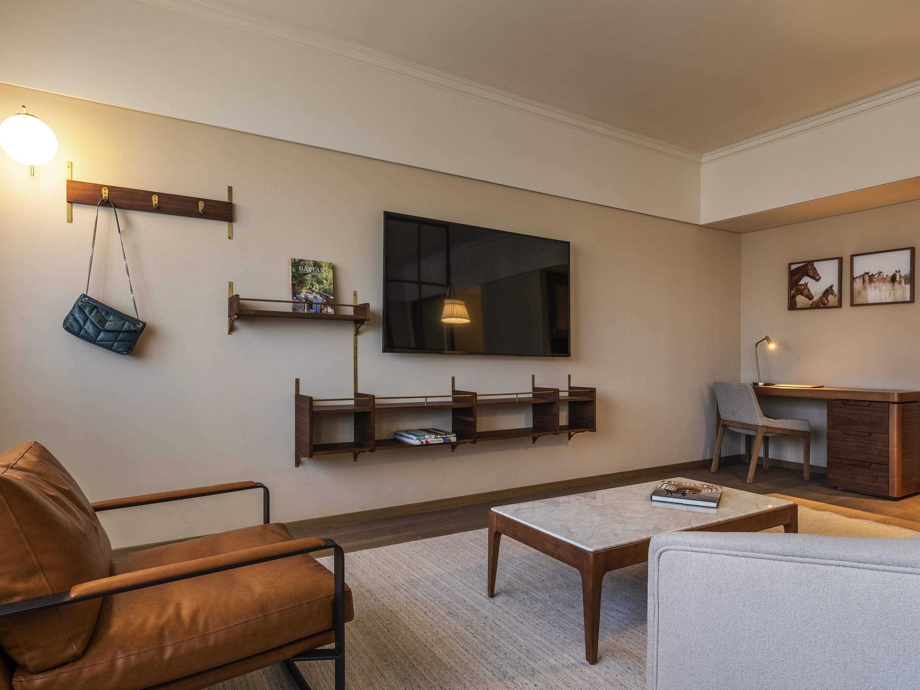 A modern living room with a sofa, coffee table, TV, and wall-mounted shelves.