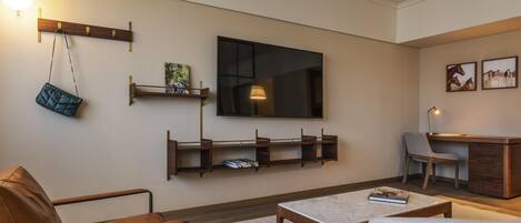 A modern living room with a sofa, coffee table, TV, and wall-mounted shelves.