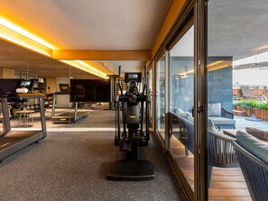 Ein modernes Fitnessstudio mit Trainingsgeräten, Laufband und Fernseher.