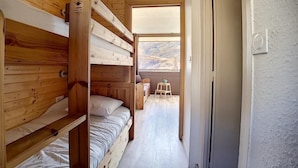 Eine Holzhütte mit Etagenbetten, einem kleinen Hocker und einem Fenster mit Blick.