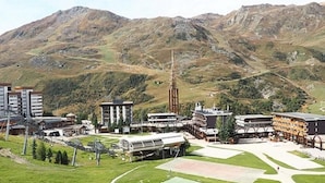 Eine gebirgige Landschaft mit einem Gebäudekomplex, der einen markanten Turm, Sportplätze und verschiedene Bauten umfasst.