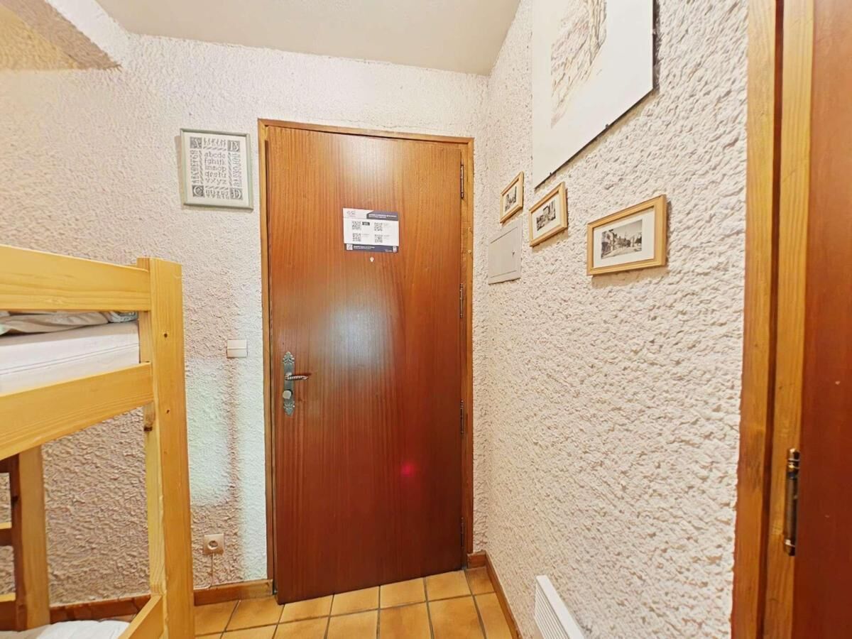 A room with a wooden door, a bunk bed, and a tiled floor.