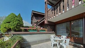 Eine Terrasse im Freien mit Tisch und Stühlen, ein Holzdeck und Blick auf einen Berg.