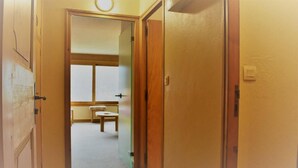 Passadís estret que condueix a una habitació amb vàter i finestra.