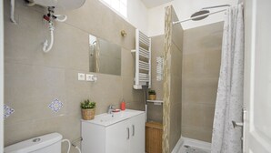 Ein Badezimmer mit Toilette, Waschbecken, Dusche und Spiegel.