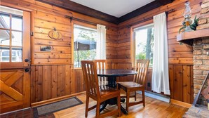 A wooden cabin interior with a dining table, chairs, and a fireplace. - Home away from Home (South Bend)
