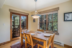 Un coin repas avec une table en bois, des chaises et un luminaire suspendu.
