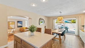 A spacious kitchen with a central island, dining area with a view of the backyard, and a living area with a sofa and chairs. - Coccoloba 3 Bedroom Home by RedAwning (Holmes Beach)