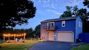 A two-story house with a balcony, a garage, and outdoor seating.