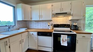 A modern kitchen with white cabinets, a black stove, and a wooden countertop.