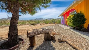 A tree in a pot, a wooden bench, and a building with a colorful exterior. - @ Marbella Lane - Rainbow House | Glampers Paradise (Joshua Tree)