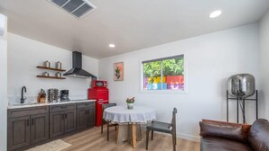 A compact kitchen with a dining area, a red microwave, and a black toaster. - @ Marbella Lane - Rainbow House | Glampers Paradise (Joshua Tree)
