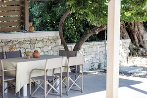An outdoor dining area with a stone wall, a wooden pergola, and a tree. - Mithonies Villa, with Private Pool & BBQ, Walking distance to shops (Rethymno)