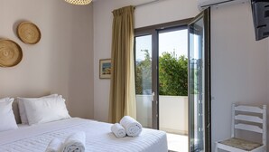 A hotel room with a bed, a chair, a window, and a door. - Mithonies Villa, with Private Pool & BBQ, Walking distance to shops (Rethymno)