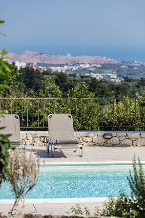 A pool area with two lounge chairs and a stone wall.