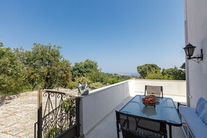 A balcony with a table, chairs, and a bowl of fruit.