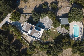 An aerial view of a property with a swimming pool, a patio area, and a large open space with a stone wall. - Mithonies Villa, with Private Pool & BBQ, Walking distance to shops (Rethymno)