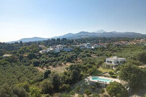 A residential area with modern houses, a swimming pool, and a mountainous backdrop.