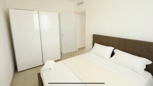 Um quarto com uma cama, um guarda-roupa e uma porta.
