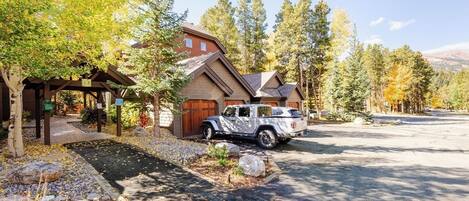 A house with a driveway, a covered outdoor area, and a vehicle parked in front.