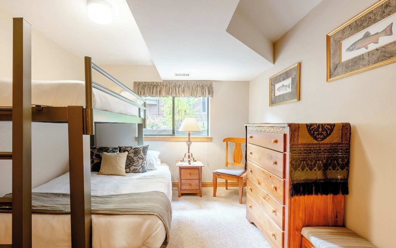 A compact bedroom with bunk beds, a small desk, a chair, and a dresser.