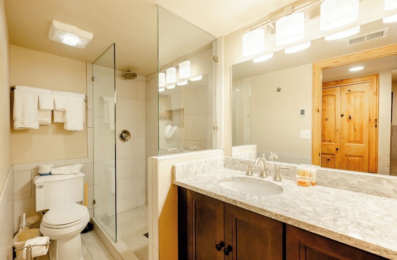A modern bathroom with a glass shower enclosure, a double sink vanity, and a large mirror.