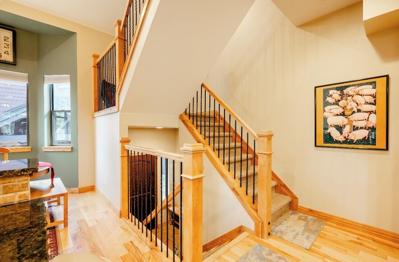 A staircase with wooden railings leading to an upper floor, a dining area with a granite countertop, and a framed picture on the wall.