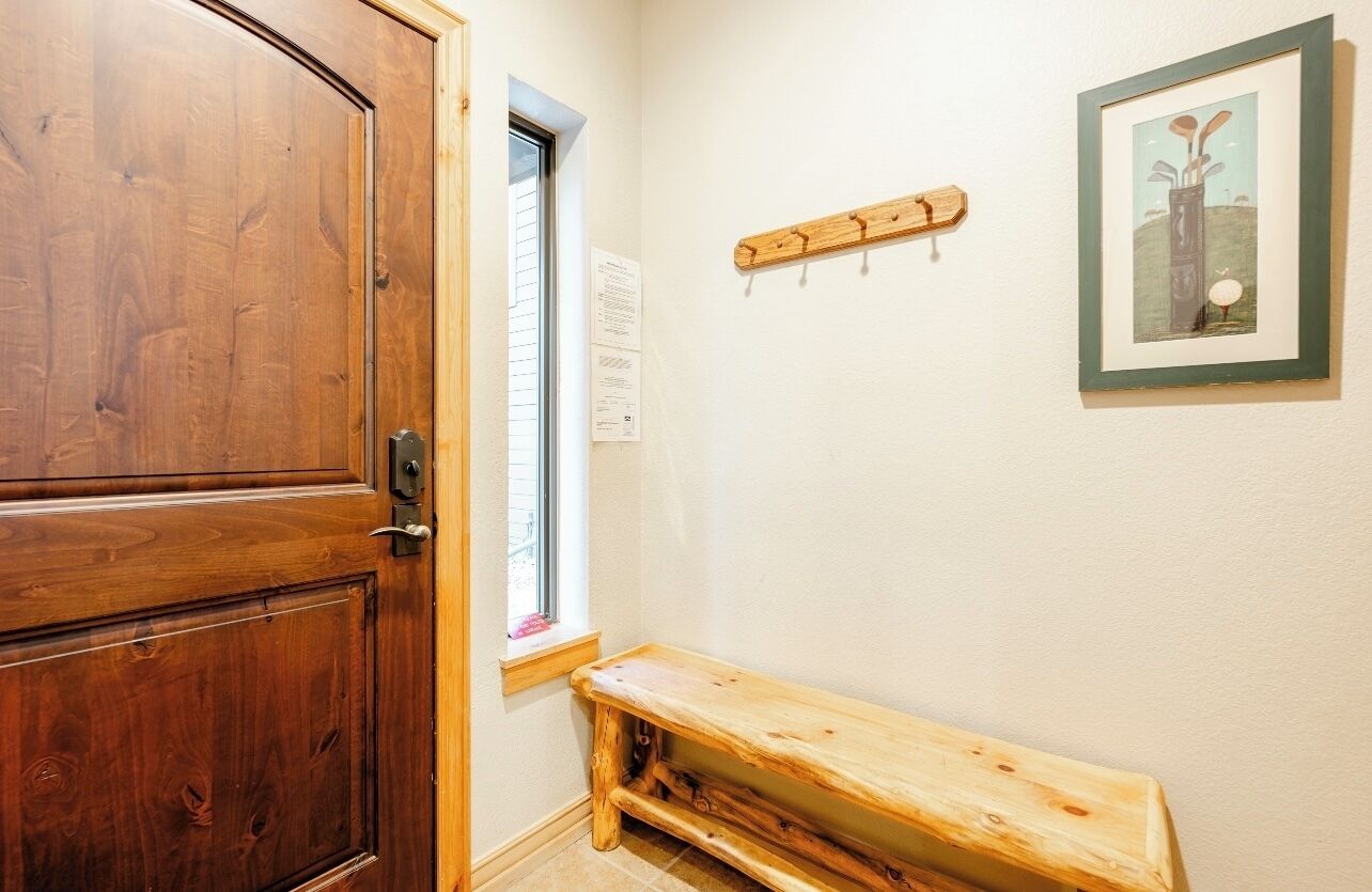 A wooden door, a bench, a window, and a framed picture on the wall.