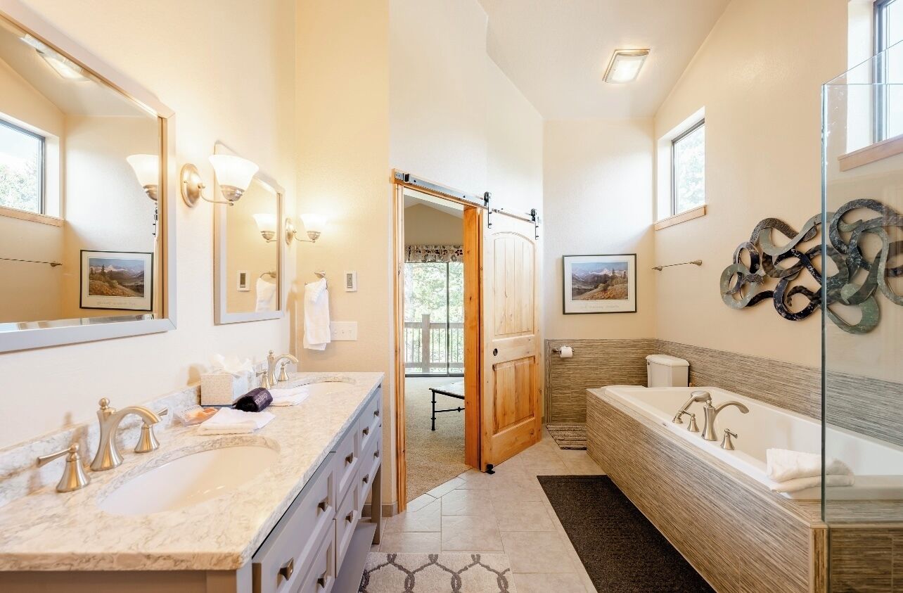 Un baño moderno con dos lavamanos, una bañera grande y cabina de ducha de vidrio.