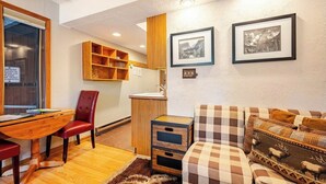 A cozy living room with a wooden desk, a red chair, a checkered sofa, and two framed pictures on the wall. - Four O'clock Lodge B05 (Breckenridge)