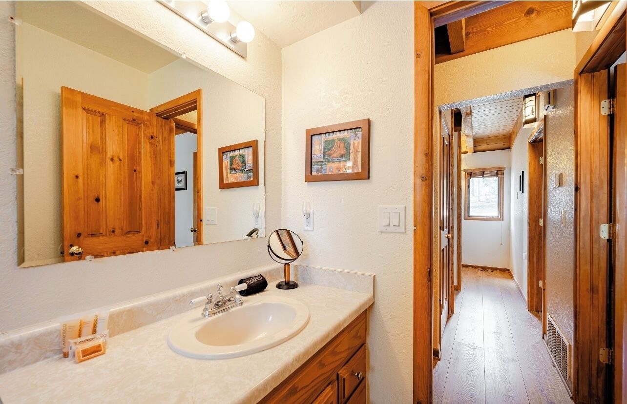 Une salle de bain avec une porte en bois, un grand miroir et un lavabo.